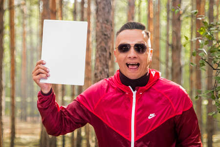 Belarus, Minsk region - June 29, 2019: Portrait of a happy smiling man with open mouth in sunglasses and a red jacket, mock up.のeditorial素材
