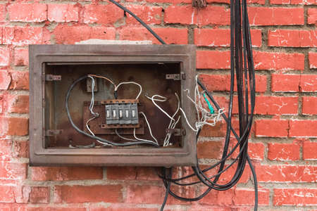 Niche of an old broken electrical panel on the background of an old red brick wall texture.の写真素材