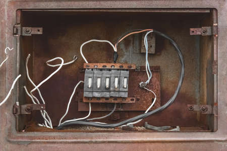 Niche of an old broken abandoned electrical industrial panel with wires, close up.の写真素材