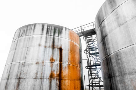 Old fuel oil tanks with fuel oil stains and traces of rust at an abandoned industrial plant.の写真素材