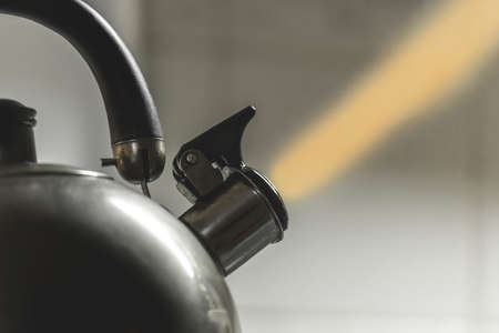 A metal kettle with a whistle heats the water to a boil on a gas stove in the kitchen, close up.の写真素材
