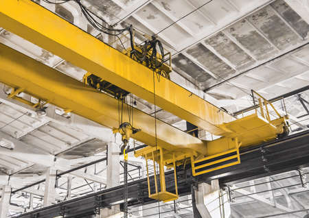 Part of an overhead building equipment crane in the background of an industrial workshop.の写真素材