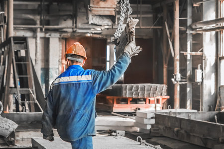A working man in a reinforcement workshop controls equipment for moving metal structures.