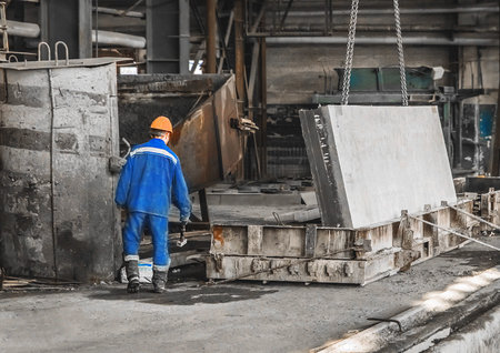 Worker in a reinforcement workshop controls equipment for moving concrete and metal structures.