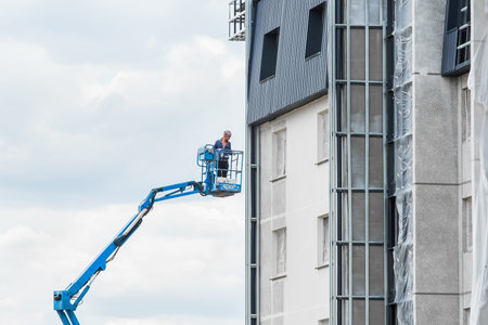 Belarus, Minsk - May 28, 2020: Industrial worker on a lifting platform near a new facade of a house...