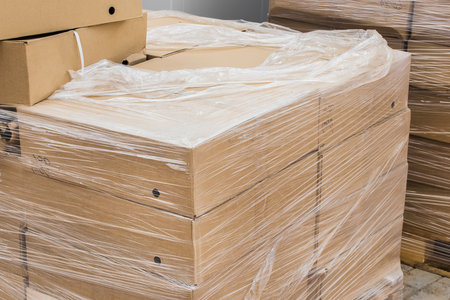 A bunch of cardboard boxes with building materials packed in plastic wrap at construction site.の写真素材