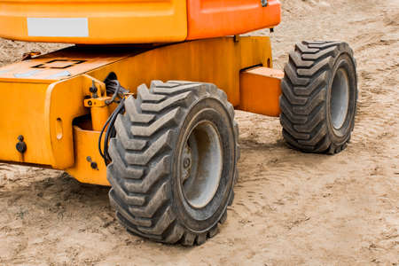 Wheels of industrial lifting transport tire truck against the background of sand at a construction site.の写真素材