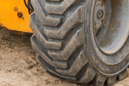 Wheels of industrial lifting transport tire truck against the background of sand at a construction...