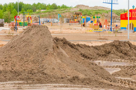 A pile of sand nature material at a construction site. Reconstruction or building a new modern playground outdoor on urban street.の写真素材