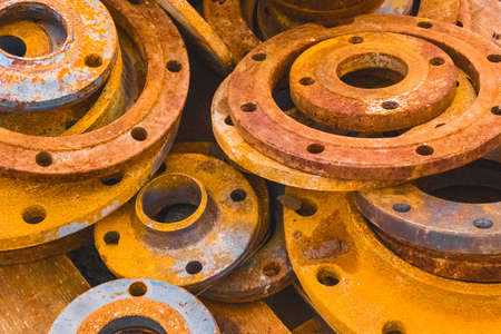 Pile of old, rusty pipe industrial flanges at a construction site.の写真素材
