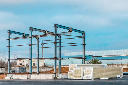 Metal frame of a new modern building under construction and packed sandwich panels at a construction...
