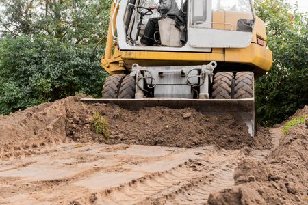Excavator or bulldozer bucket flattens the ground or road in the industrial zone or construction...