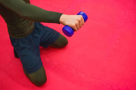 The guy in a thermal suit and shorts does exercises with dumbbells in the gym.の写真素材