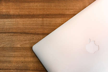 Belarus, Minsk region - March 17, 2020: Apple laptop on a wooden table texture background.のeditorial素材
