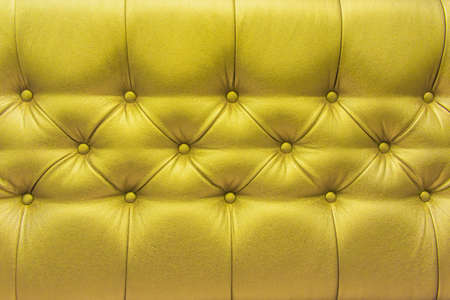 Yellow or gold leather upholstery sofa with pattern button design furniture style decor texture background.の写真素材