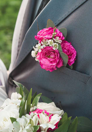 Pink rose boutonniere on the groom's gray suit, close-up, wedding element of the man's decor.の写真素材