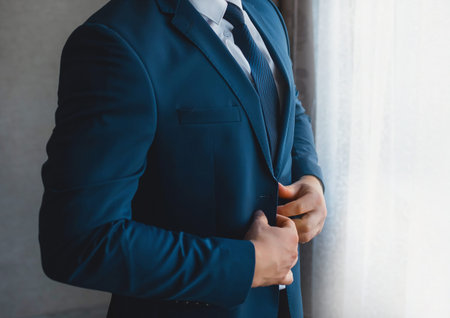 Business and serious man businessman in white shirt, blue tie and suit stands at the window.の写真素材