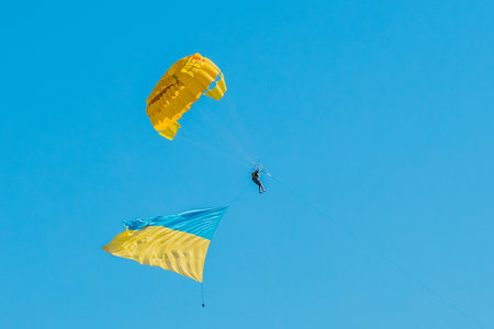 Parashutist in the blue clear sky flies with the Ukrainian national symbol flag background.の写真素材