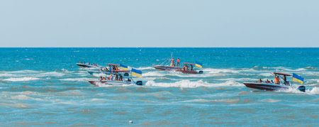 Ukraine, Iron Port - August 24, 2020: A group of Ukrainian people and tourists on boats or ships sail across the sea with Ukrainian symbols flag.のeditorial素材