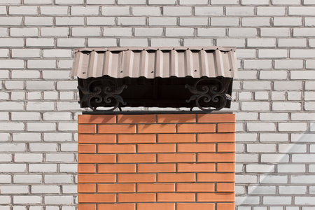 Red or brown brick architectural element on the background of white brick exterior facade of the...