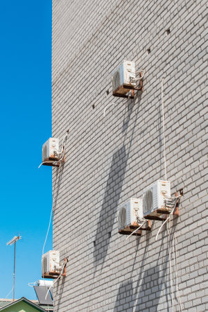Air conditioning equipment for cooling of the air modern technologies on the wall of a white brick building against the blue sky.の写真素材