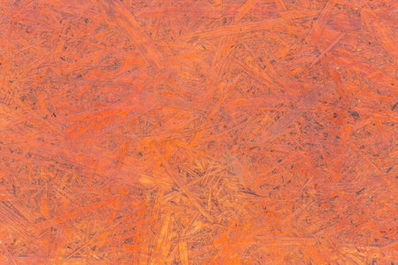 Red chipboard brown particleboard pattern pressed wood material surface texture background.