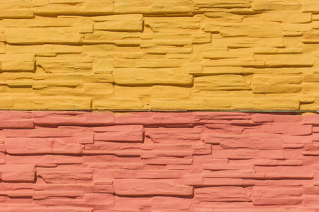 Yellow and red paint on surface stone tile bright wall modern texture background.