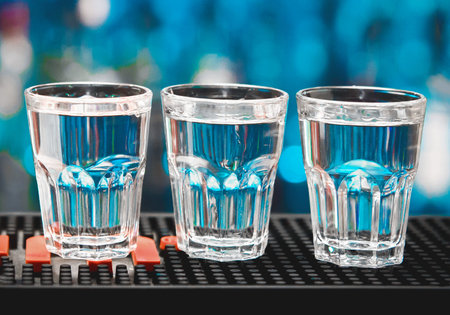 3 glasses of Russian chilled vodka alcohol on the bar counter of a nightclub, close-up.