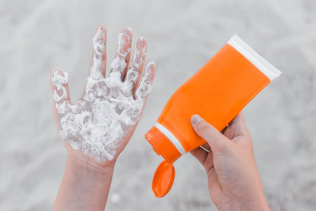 The girl holds sunscreen, in her hand and squeezes it on her arm palm to protect her from the sun...