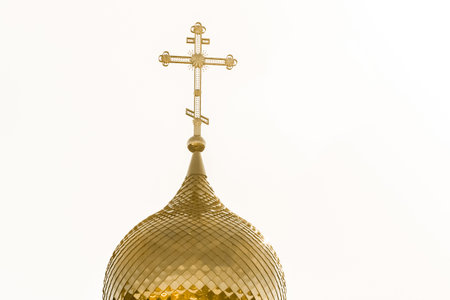 Golden dome of the church with a cross religious architecture against the sky.