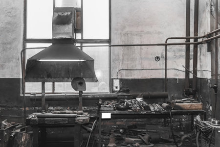 Old workshop with workbench and tools of industrial plant and large vetillation pipe with access to...