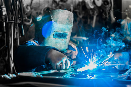 Male welder worker at the plant is engaged in welding and metal work in the shop.