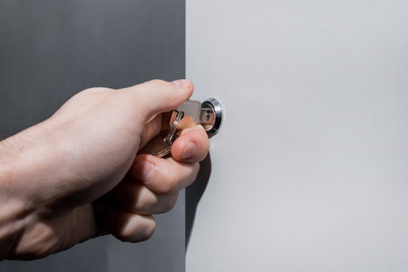 The hand of a human electrician opens or closes the electrical box with a metal key. Safe...