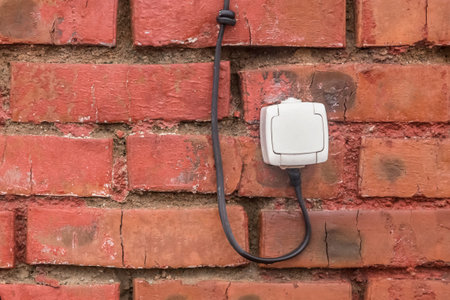 Old white socket on a reddish-brown brick wall background.