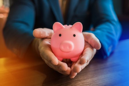 The hand of a businessman holds a pig piggy bank for storing and saving money and finances.の写真素材