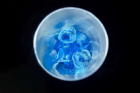 Blue cold syrup with ice in a tool for mixing and making alcoholic cocktails shaker on a black background, close-up.の写真素材