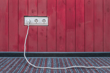 Connect the power and energy plug cable to the outlet on the red wooden wall surface.