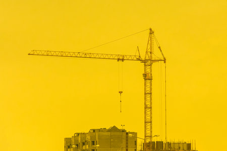Construction industrial crane against the backdrop of a yellow sunny sky and sunset.の写真素材