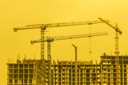 Construction industrial building crane against the backdrop of a yellow sunny sky and sunset development.の写真素材