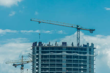 Tower cranes build and development new urban houses architecture industry on blue sky background.の写真素材