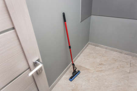 Mop stands against the wall and floor cleaning of production facilities. Household chores and hygiene of sanitary facilities.の写真素材