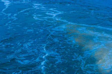 The surface of the lake water with a foam trace is a natural background. The process of filtering water of a dirty environment trail.の写真素材