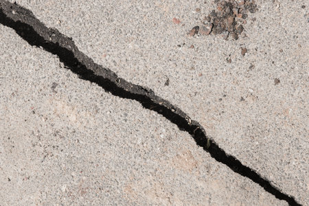Large crack stratification separation of asphalt road broken damaged stone surface.