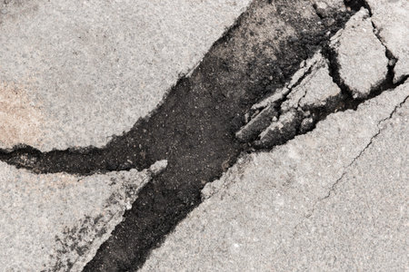 Large crack stratification separation of asphalt road broken damaged stone surface.
