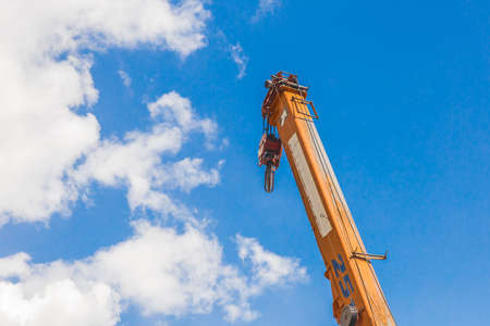 Lifting hoisting mechanism with rope steel of the machine bridge crane with iron cable and hook on a blue sky background.の写真素材