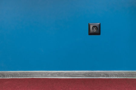 Double black socket power home energy supply electricity on blue wall background and skirting board...