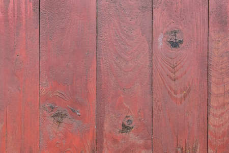 Old wooden worn fence boards weathered texture in peeling red paint dirty obsolete background.の写真素材