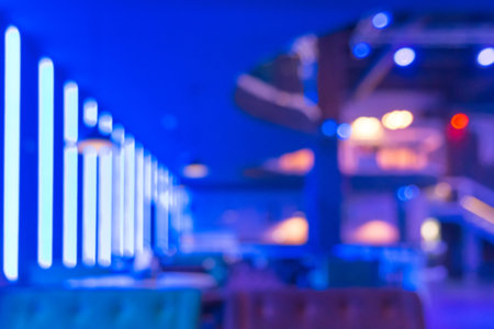 Blurred modern abstract interior of a nightclub with neon blue lighting on the walls.