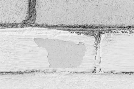 White old paint peeling brick obsolete wall weathered texture worn background.
