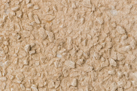 Sand yellow beige color paint on stone pebble surface solid texture wall background.
